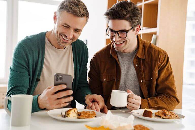 A couple looks at a phone while they are eating breakfast