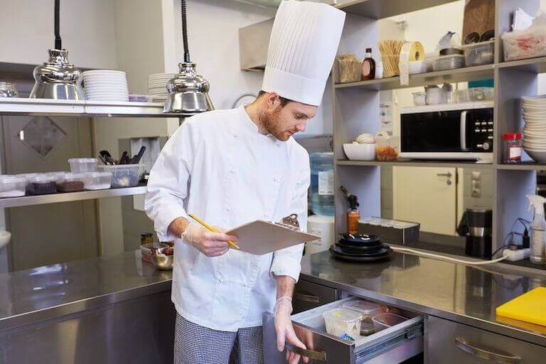 Chef with clipboard doing inventory in a kitchen