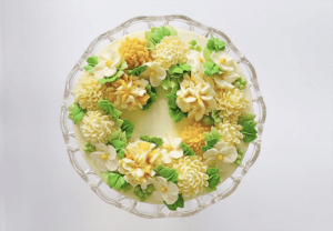 Top view of White Chocolate Buttercream cake with yellow flowers and green leaves