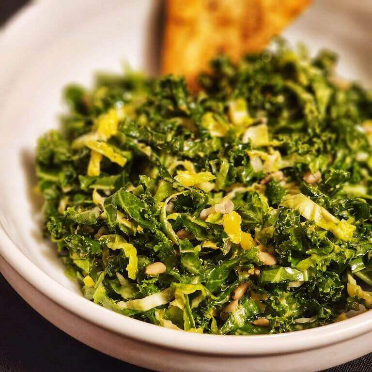 kale and brussels sprouts salad with zesty vinaigrette, toasted sunflower seeds, and nutritional yeast