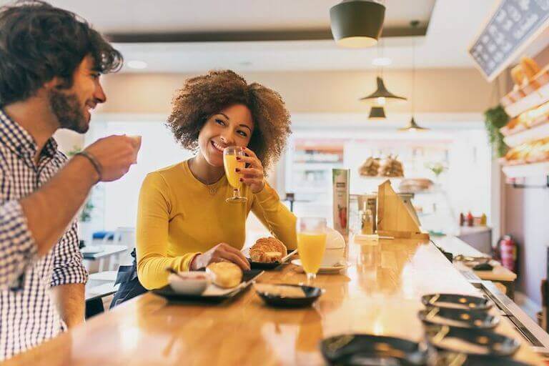 Two people at a cafe having orange juice and croissants