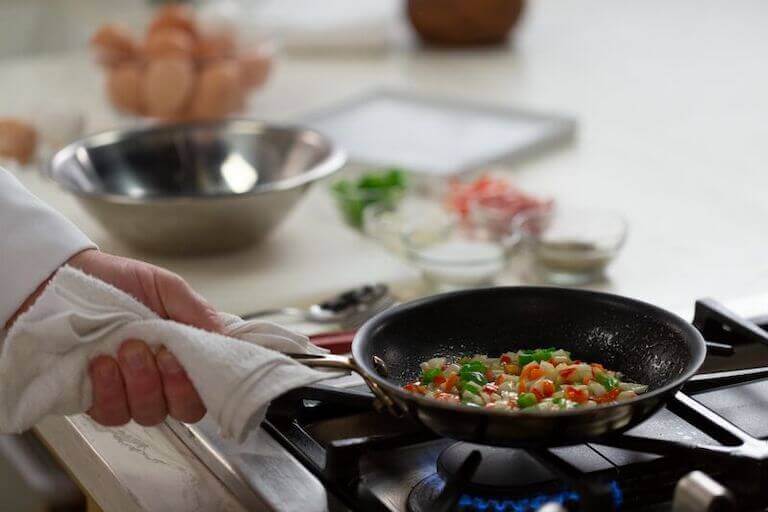 Onions and peppers being sauted in a pan