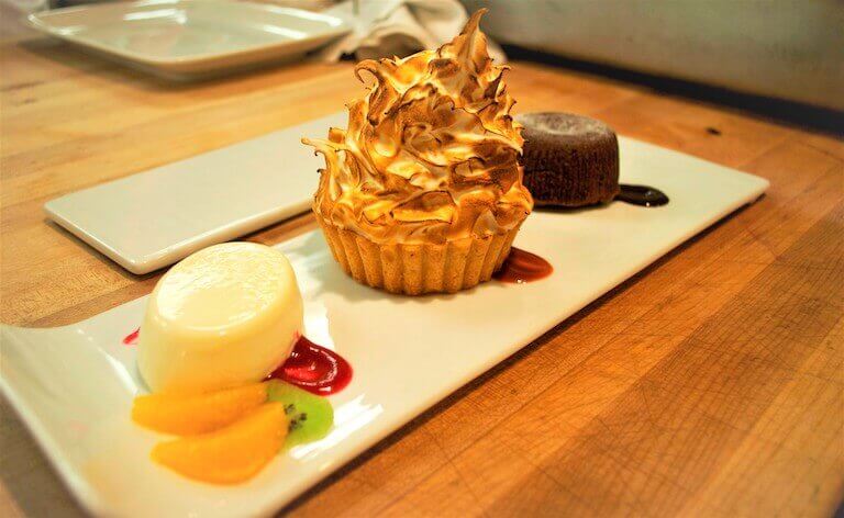 Panna cotta with fruit and a strawberry sauce, lemon meringue tart with raspberry sauce, and a chocolate lava cake with chocolate sauce by Chef Eric