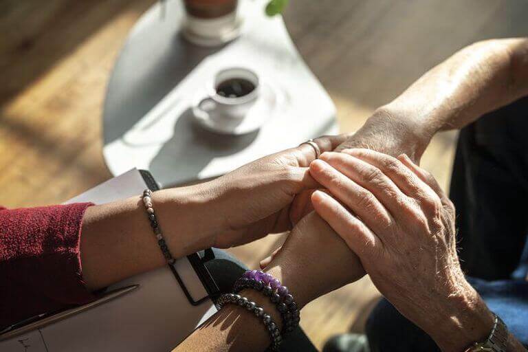 psychologist holding elderly patient's hands