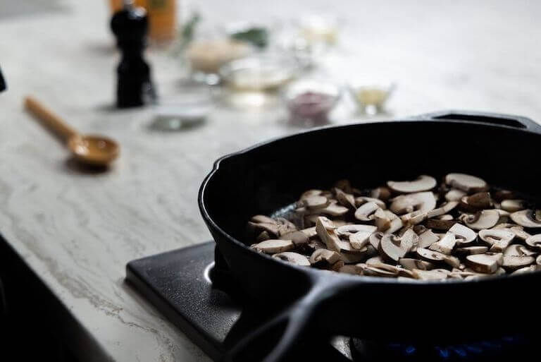 Sliced mushrooms in a cast iron pan on the stove