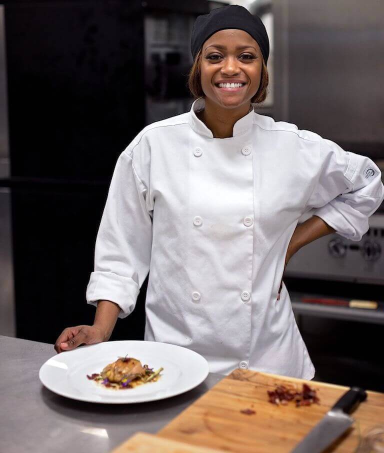 Student smiling and standing in a commercial kitchen