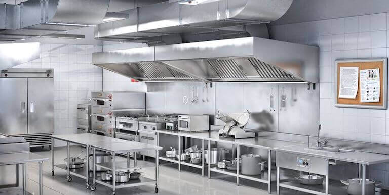 Interior of a professional kitchen with clean metal surfaces and a corkboard containing two white text-only posters.