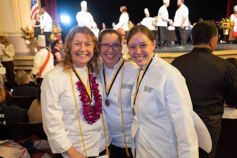A small group of students and faculty smiling during graduation at Escoffier’s Boulder campus.