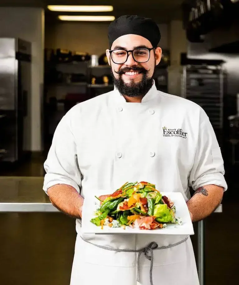 Chef working in a kitchen and showing his plate