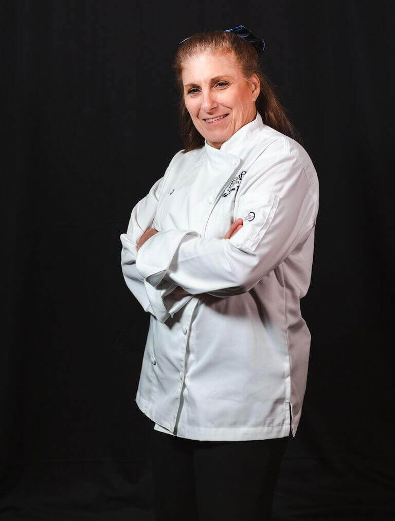 Chef Instructor Dawn DeStefano, smiling with hands folded. 