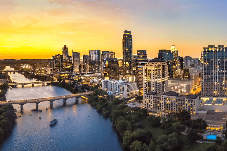 A view of the Austin, Texas skyline with the sun setting in the background.