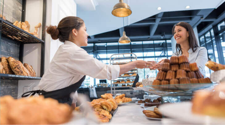 A smiling woman buying pastries at a bakery