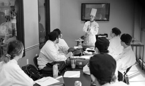 Escoffier Chef Instructor giving a lecture to culinary students in a classroom