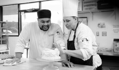 Escoffier pastry arts chef instructor reviewing student's cake