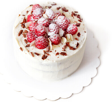 Raspberry white cake decorated with fresh berries on a cake stand