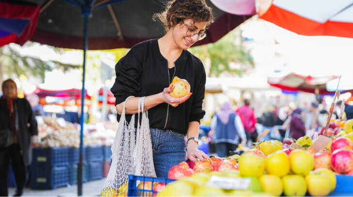 Woman with a net in her hand shopping for fruits and vegetables at the local public market