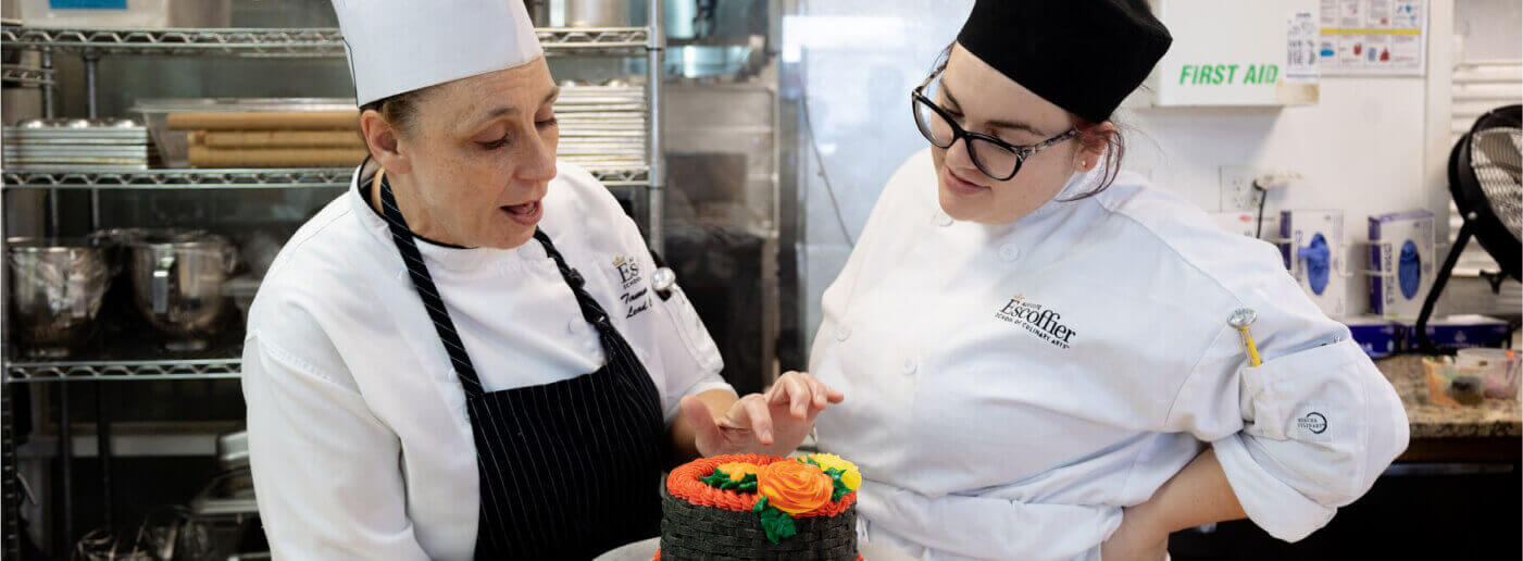 An Escoffier Austin chef instructor reviews a frosted cake prepared by a baking & pastry student