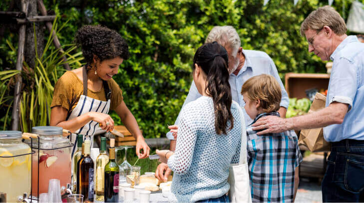 A vendor gives customers cheese tastings at a farmers market