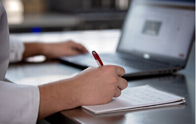 An online culinary student taking notes in front of a computer notebook