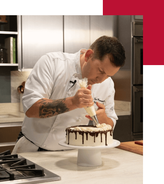 Chef Instructor Steve Konopelski piping whipped cream on a cake