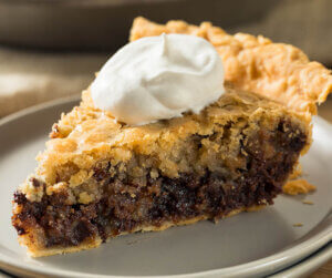 Kentucky Derby Chocolate Walnut Pie on a plate with whip cream dollop.