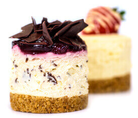 Two mini cheesecake desserts with Graham cracker crust and chocolate and berry toppings