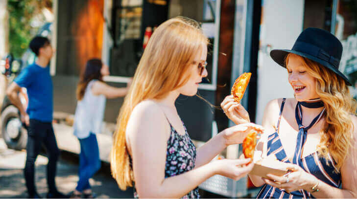 Two young revelers enjoy fried food at a food festival