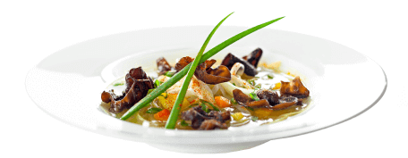 Curry chicken soup with mushrooms and chives in a white bowl