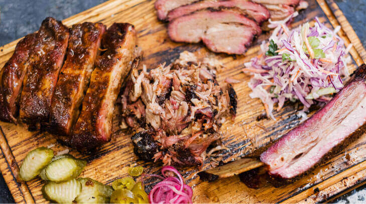 Smoked meat assortment with beef brisket and pulled pork on a wood board