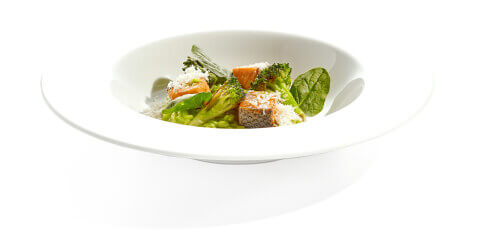 Green risotto with broccoli and pan-seared salmon in a white bowl plate