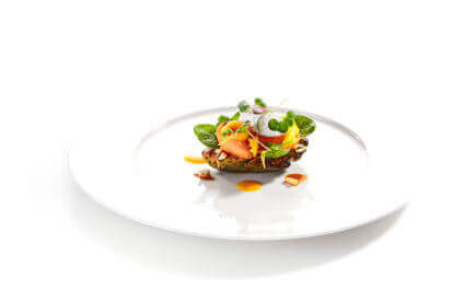 Grilled avocado with mozzarella, cream, and sun-dried tomato jam on a white plate