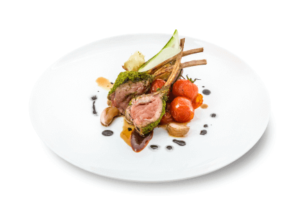 Lamb chops with greens and cherry tomatoes with sauce on a white plate