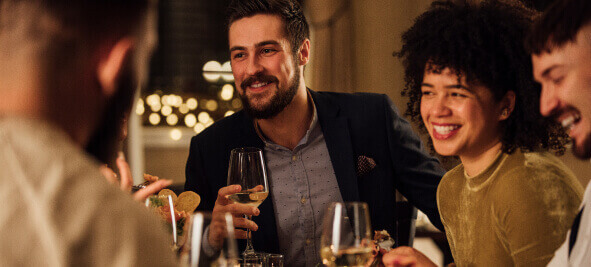 A group of friends laugh at a restaurant dining table