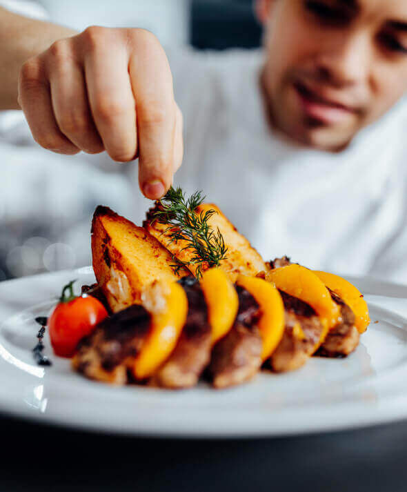 A close-up of a chef finishing a restaurant plate with fresh dill