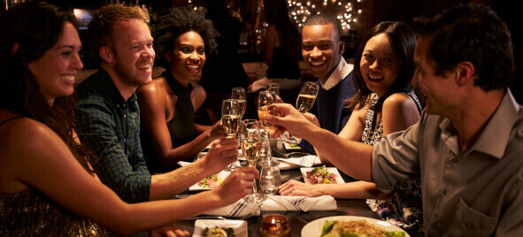 A group of happy diners toast with champagne in a trendy restaurant