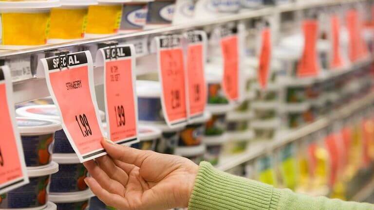A woman reads a sale tag at a grocery store.