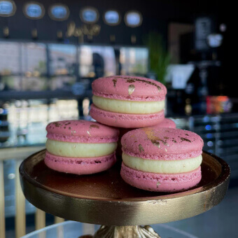 Pink macarons made by an Escoffier student sitting on a golden tray