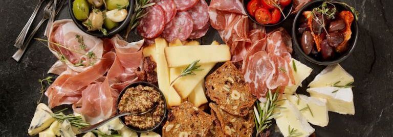 Overhead view of a charcuterie board with meats, cheeses, and olives.