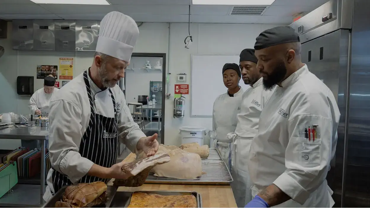 Escoffier Austin culinary students watching a chef instructor's lesson in the Escoffier kitchen