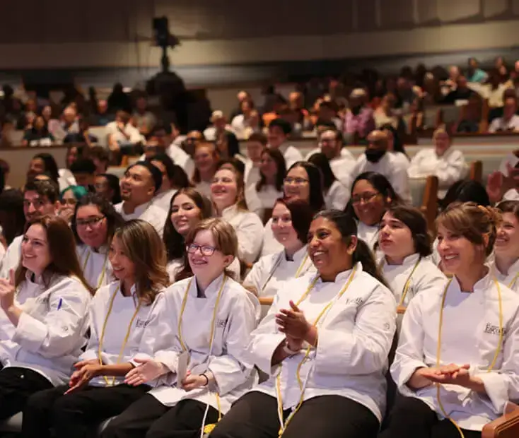 A crowd of Escoffier students smiling at the camera at a graduation ceremony