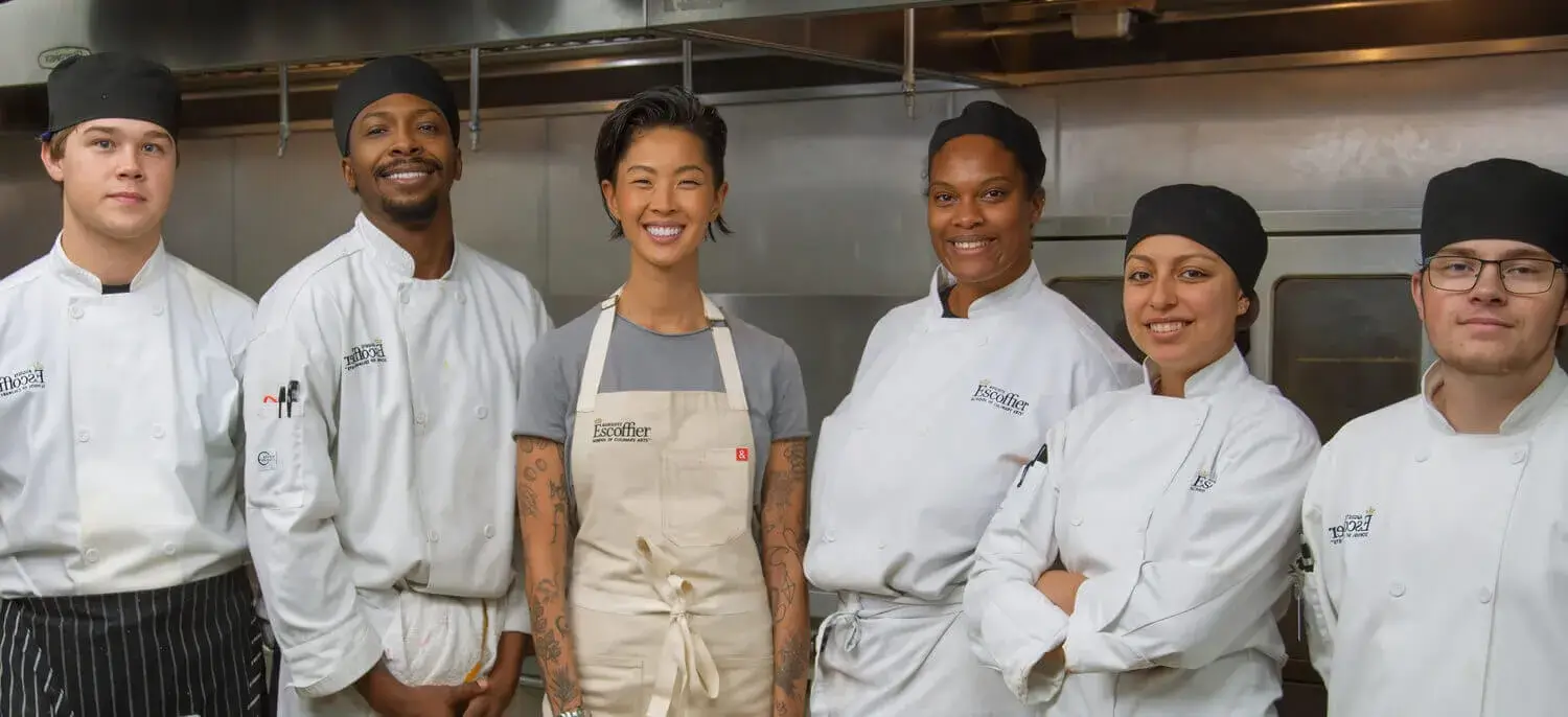 Kristen Kish stands with a diverse group of culinary students in an Escoffier kitchen