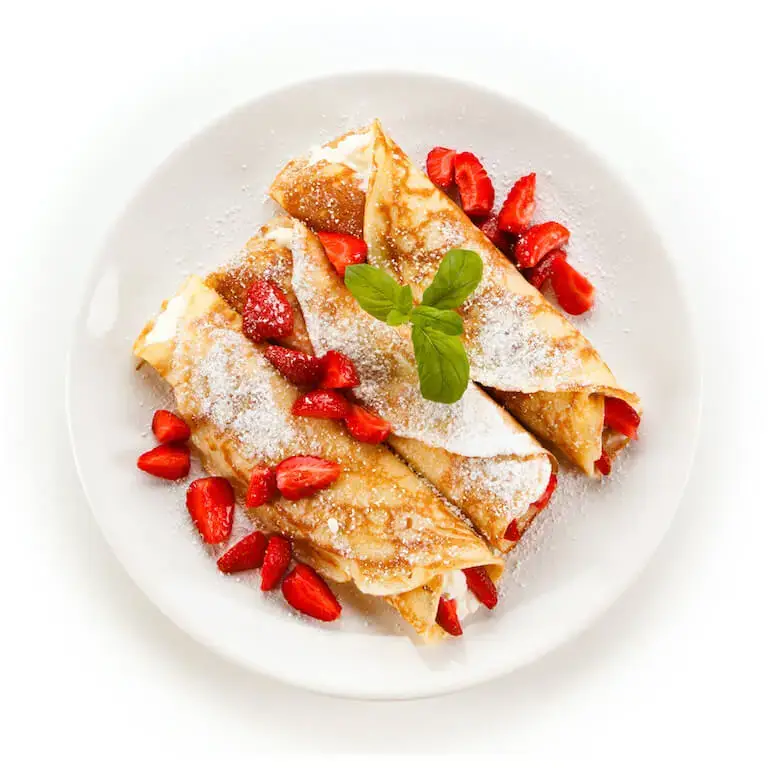 Crepes with strawberries and cream sprinkled with powdered sugar on a white plate.
