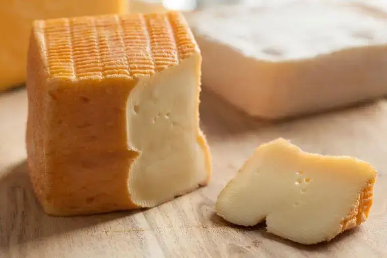 A block of limburger cheese with a slice cut out of it.