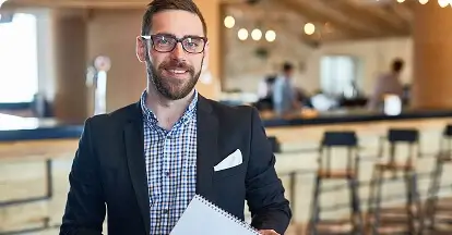 miling food & beverage manager in a suit holding a notepad inside a modern venue