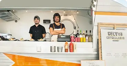 Two smiling chefs serving food at a modern food truck