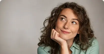 Smiling woman looking up thoughtfully with her hand on her chin