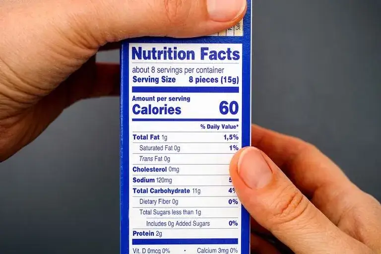 A close-up of someone holding a packaged food item, showing the nutrition facts label.