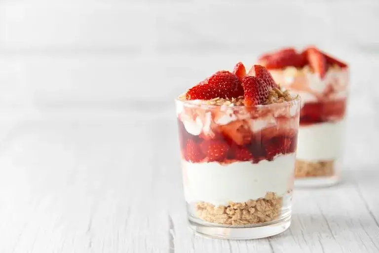 Two strawberry granola parfaits in glasses. 