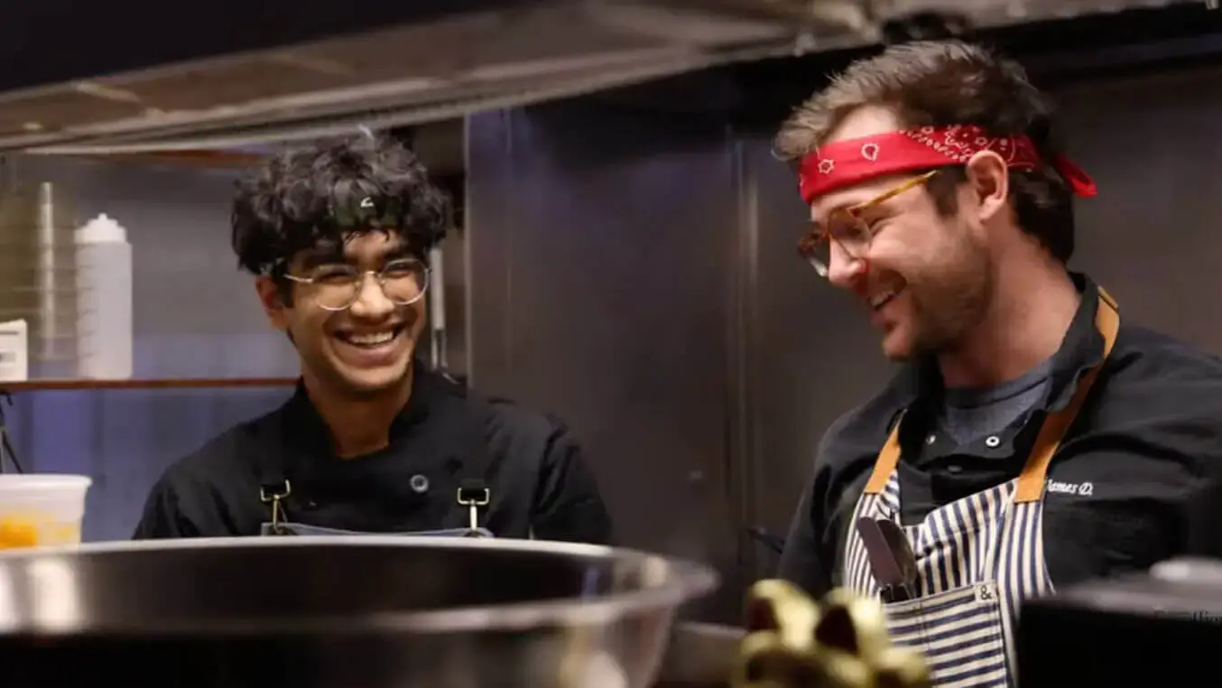 An Escoffier student Reshmanth smiling with a chef in a kitchen at a restaurant where he is doing his industry externship