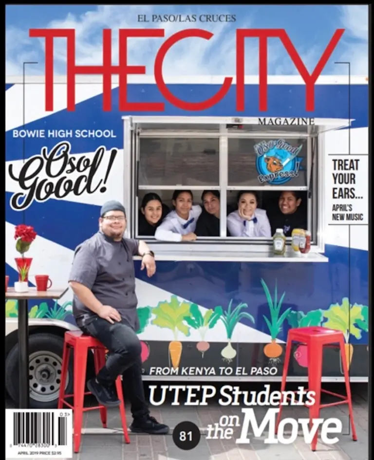 Cover of The City magazine showing Chef Chris standing outside of the food truck with students looking out the window. 